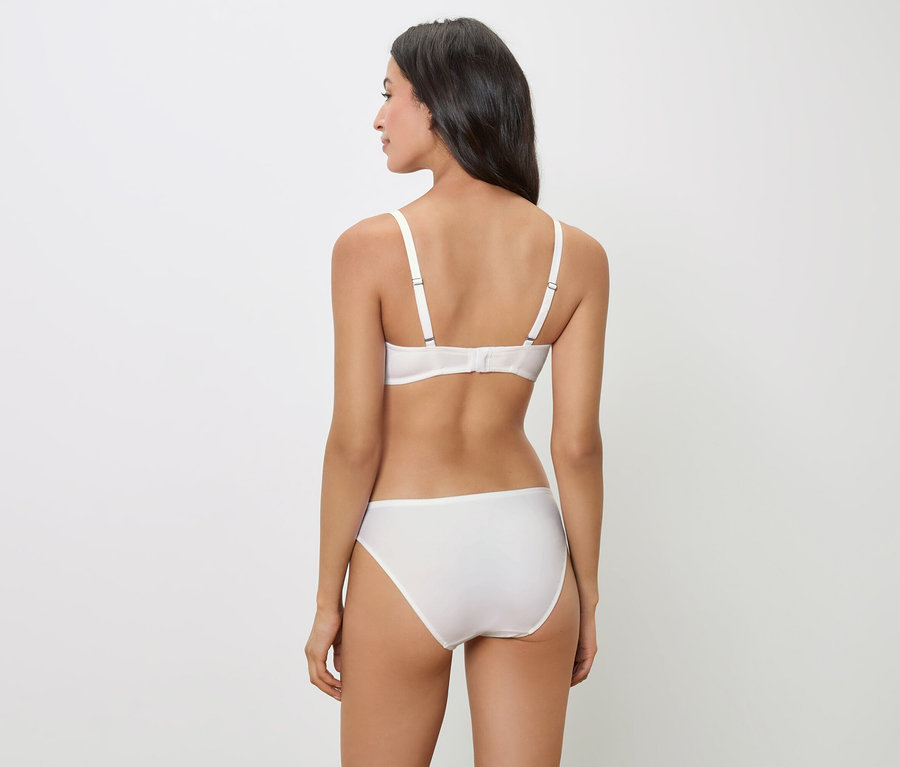 Pohľad zozadu na ženu s tmavými vlasmi, ktorá má na sebe bielu podprsenku a nohavičky.