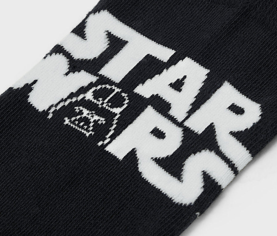 Detail čiernej ponožky s bielym nápisom STAR WARS a obrázkom Darth Vadera.