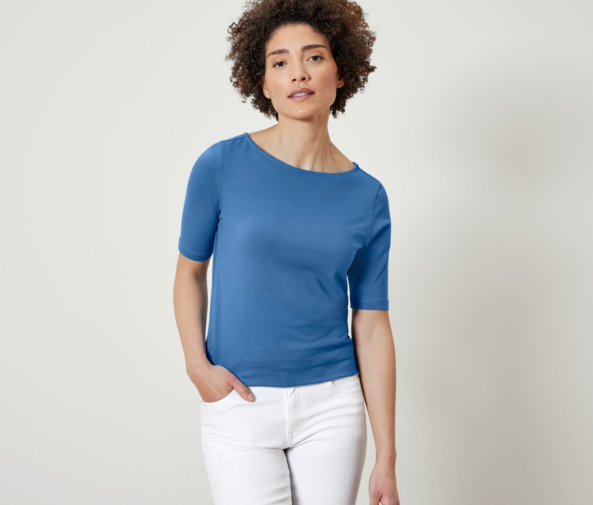 Žena pózuje v modrom tričku s polodlhým rukávom.