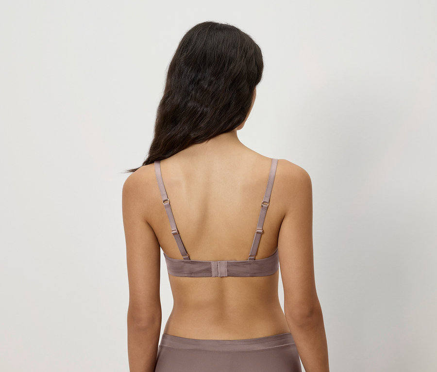 Pohľad zozadu na ženu s hnedými vlasmi, ktorá má na sebe hnedú podprsenku a nohavičky.