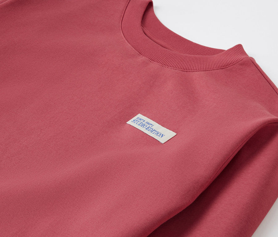 Detail detskej mikiny, červená farba, s nášivkou Studio Edition.