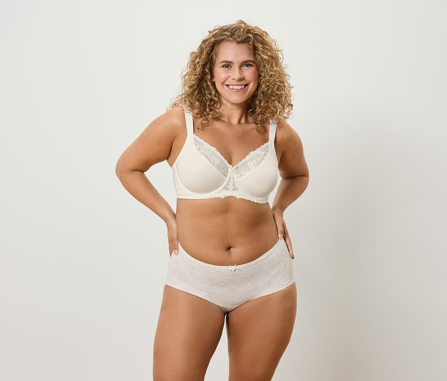 Žena s kučeravými vlasmi pózuje v spodnej bielizni.