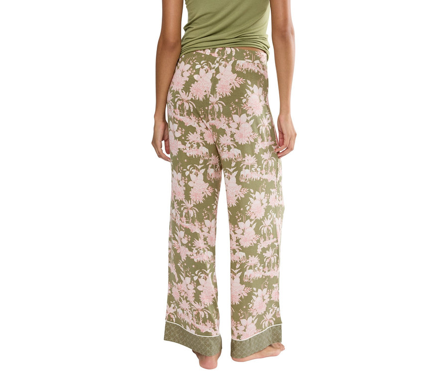 Pohľad zozadu na ženu v zelených nohaviciach s ružovým kvetinovým vzorom a zelenom tope.