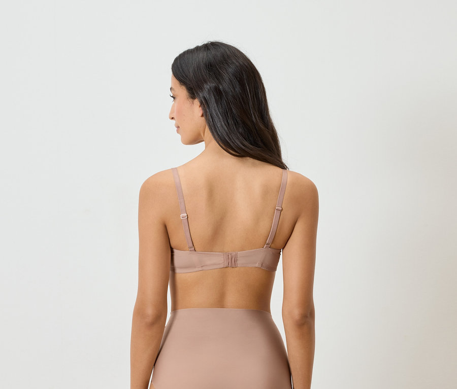 Pohľad zozadu na ženu s tmavými vlasmi v telovej podprsenke a spodnej bielizni.