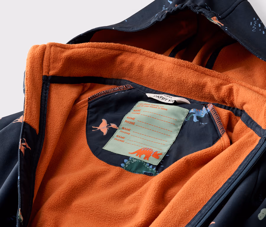 Detailný záber na otvorenú, tmavomodrú detskú bundu s dinosaurovým vzorom a oranžovou flísovou podšívkou.