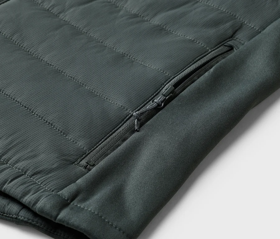Detail olivovozelenej prešívanej bundy s vreckom na zips na rukáve.