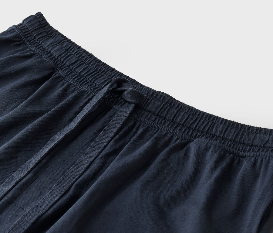 Detailný záber na tmavomodré látkové nohavice so sťahovacou šnúrkou.