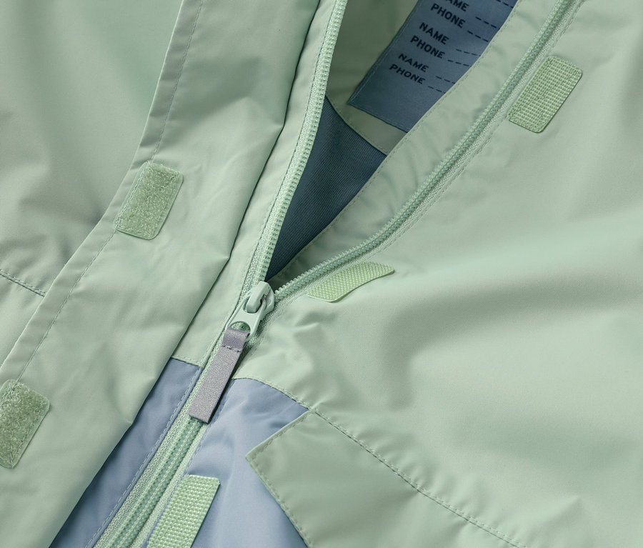 Detailný záber na rozopnutú mätovo zelenú bundu so zipsom a svetlomodrými akcentmi.