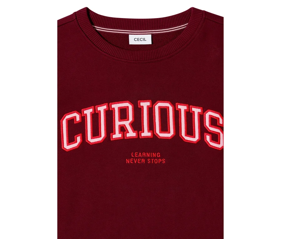 Bordová mikina CECIL s veľkým, červeno-bielym vyšívaným nápisom „CURIOUS“ a pod ním „LEARNING NEVER STOPS“.