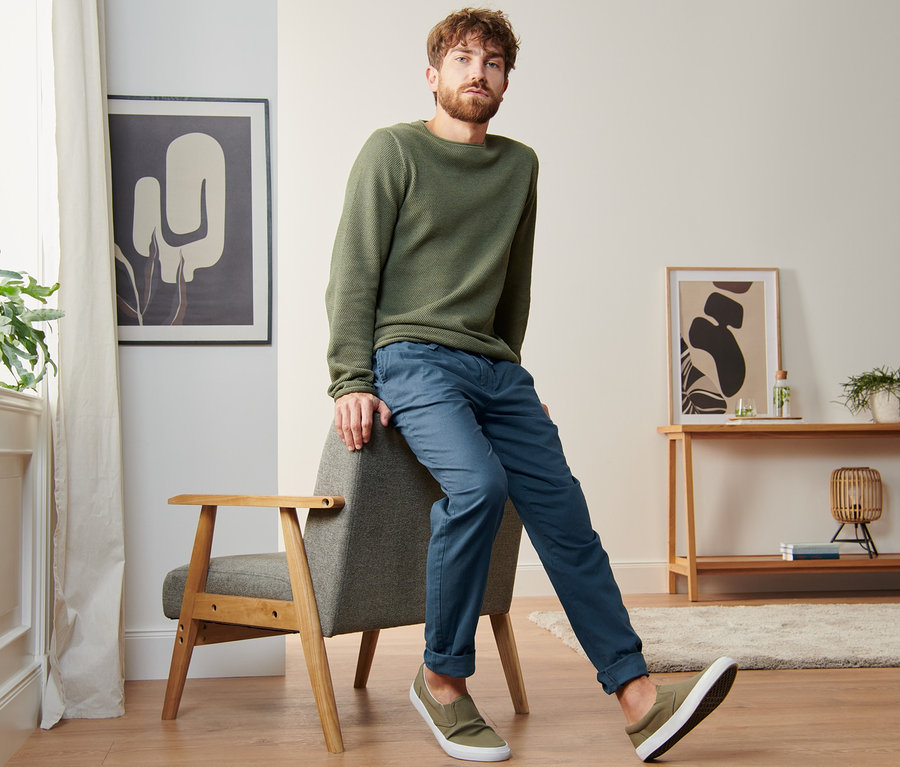 Muž sedí na stoličke a má na sebe chino nohavice s ľanom.