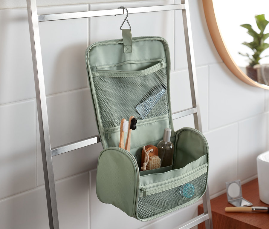 Zelená toaletná taštička visí na rebríku v kúpeľni.