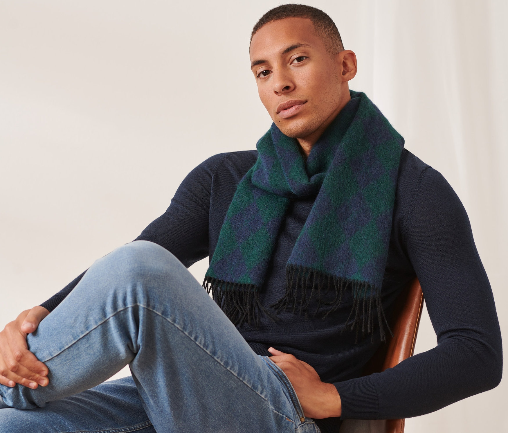 Muž sedí na stoličke a má na sebe vlnený šál.