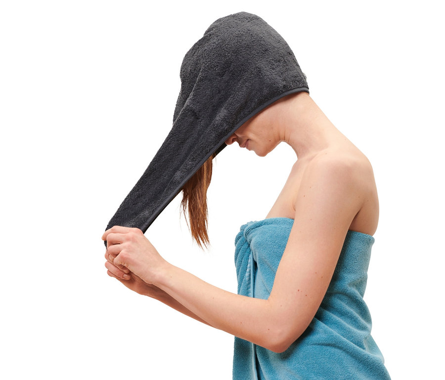 Žena si nasadzuje na hlavu antracitový uterákový turban.