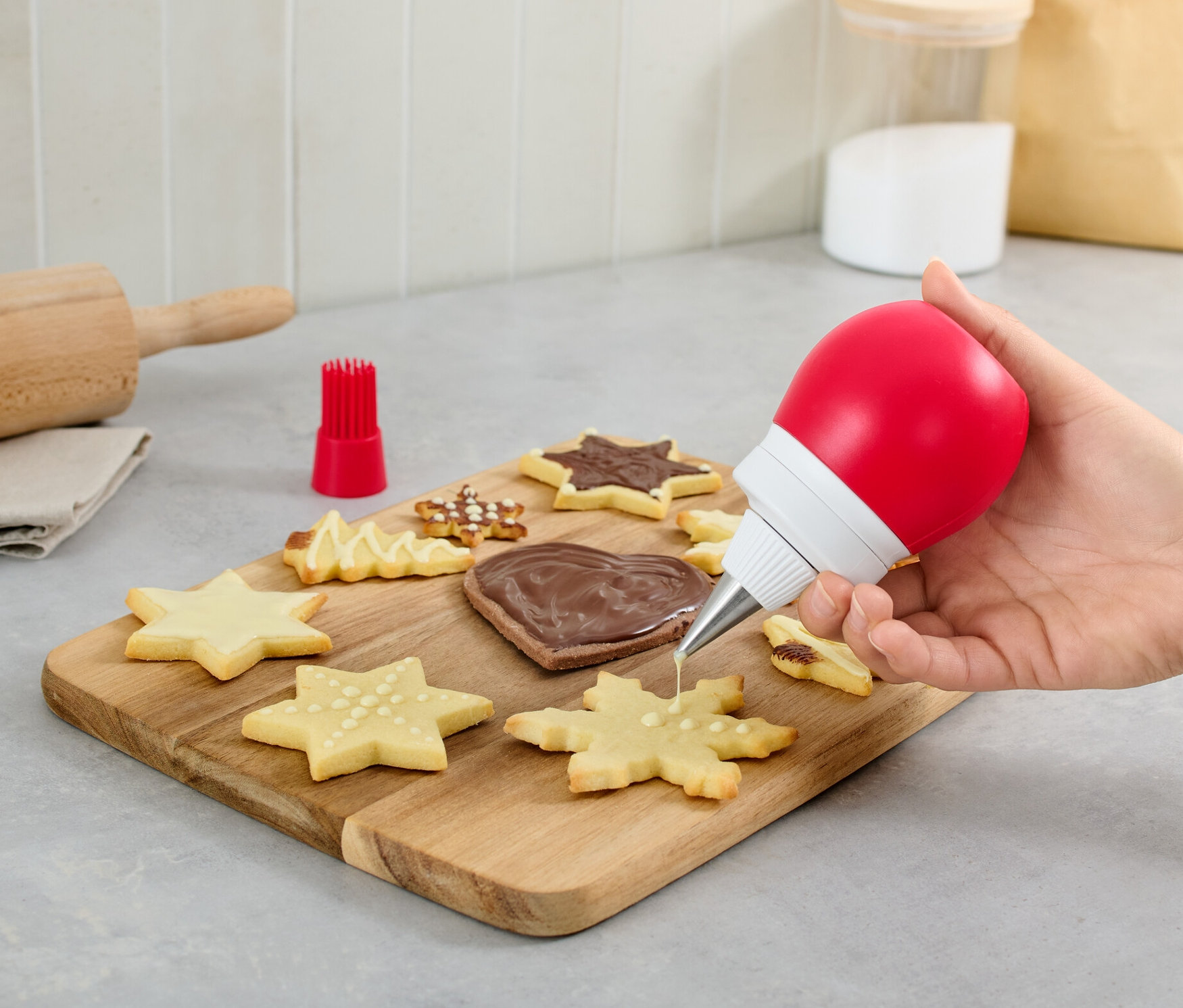 Ruka zdobí sušienku pomocou 2 v 1 ozdobnej fľaše.