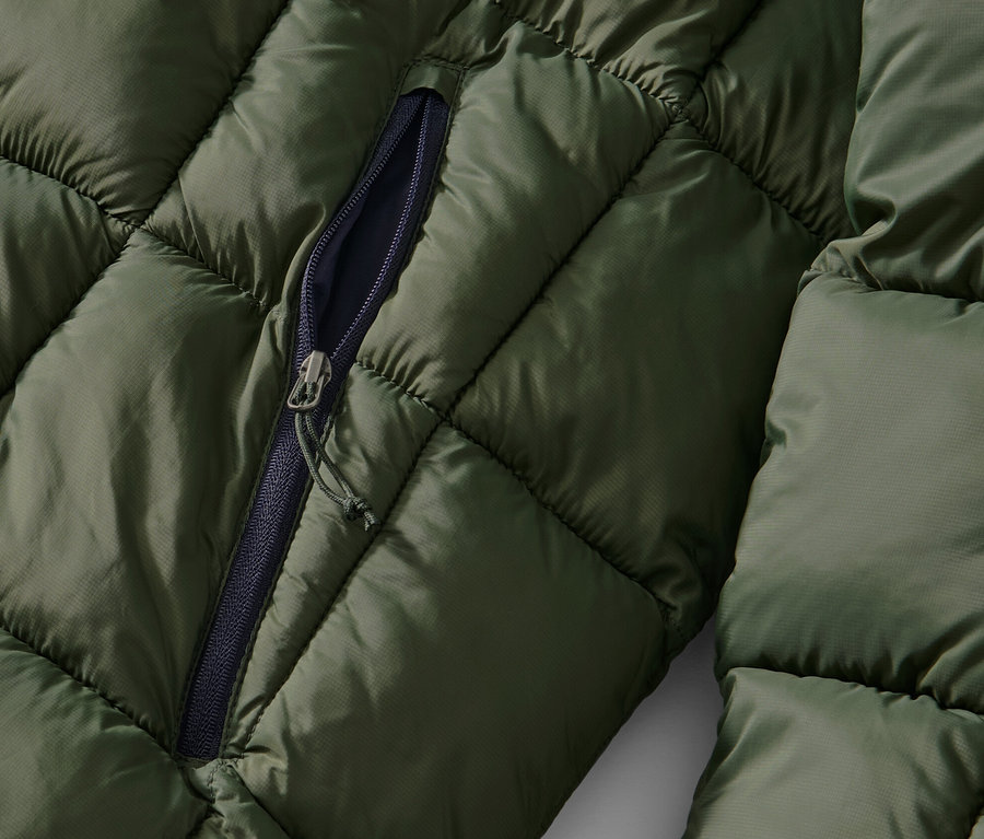Detail khaki prešívanej bundy s čiastočne rozopnutým zipsom.