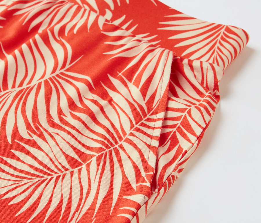Detail červených džersejových šortiek s potlačou listov.