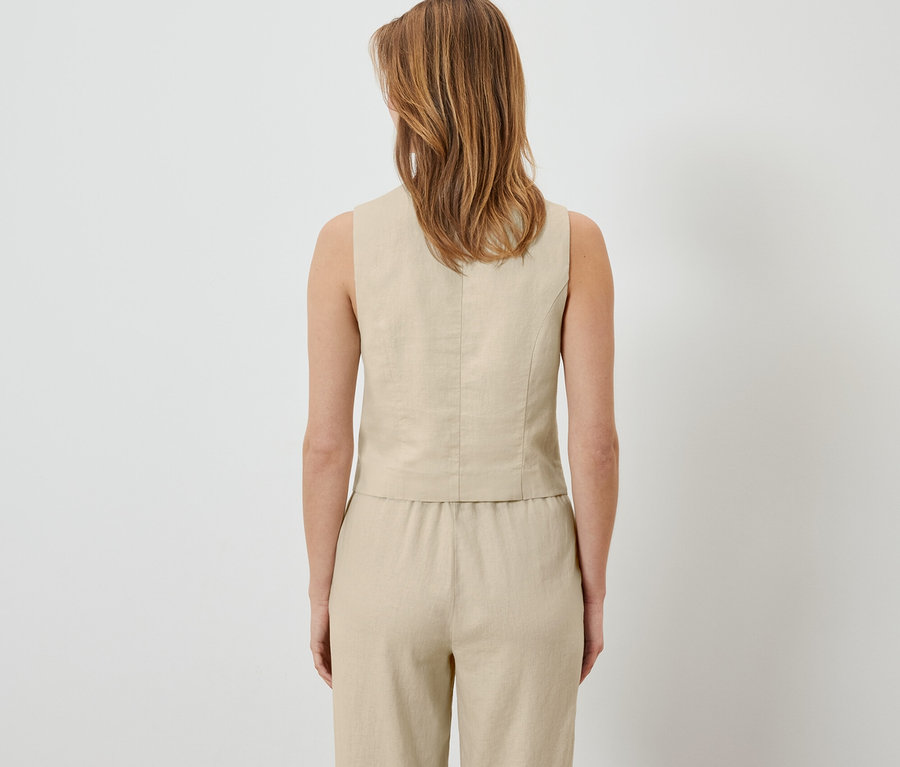 Pohľad zozadu na ženu v ľanovej veste a nohaviciach.