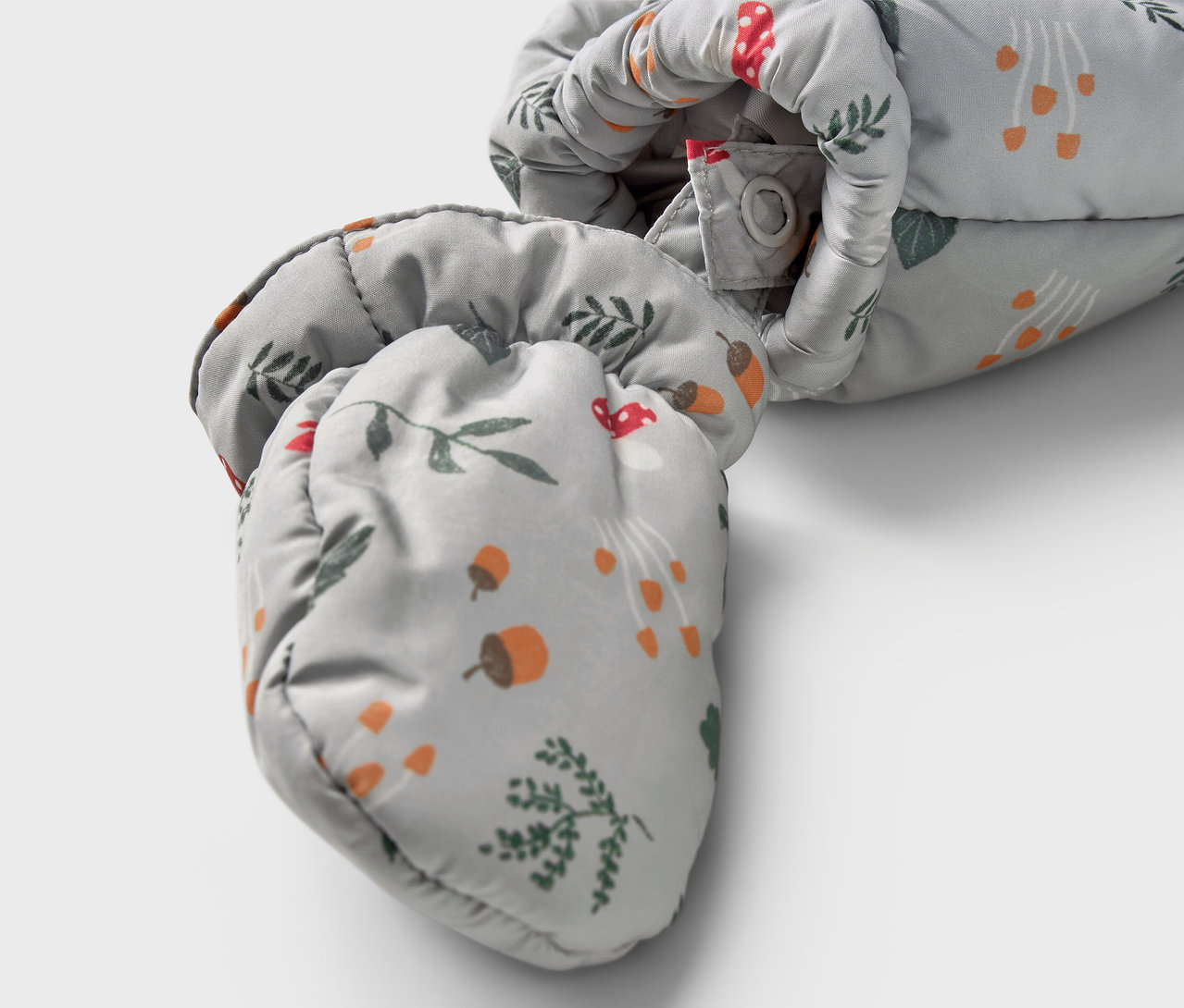 Detail detského zimného overalu s potlačou húb, žalúdov a vetvičiek.