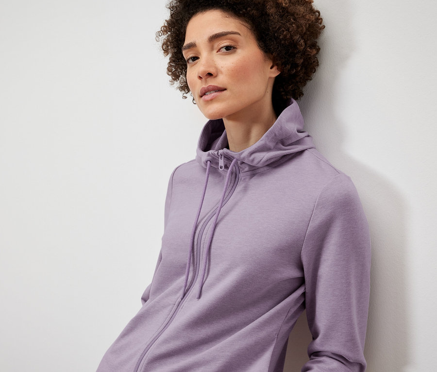 Žena pózuje v lila mikine.