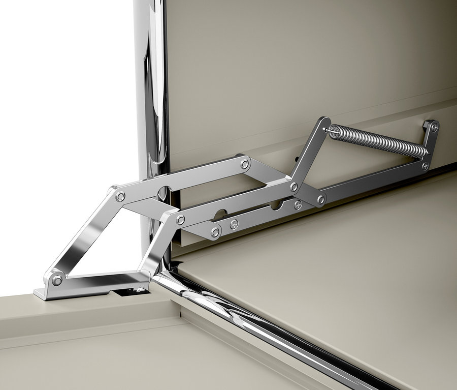 Detail chrómového mechanizmu pántu s pružinou na béžových dvierkach.