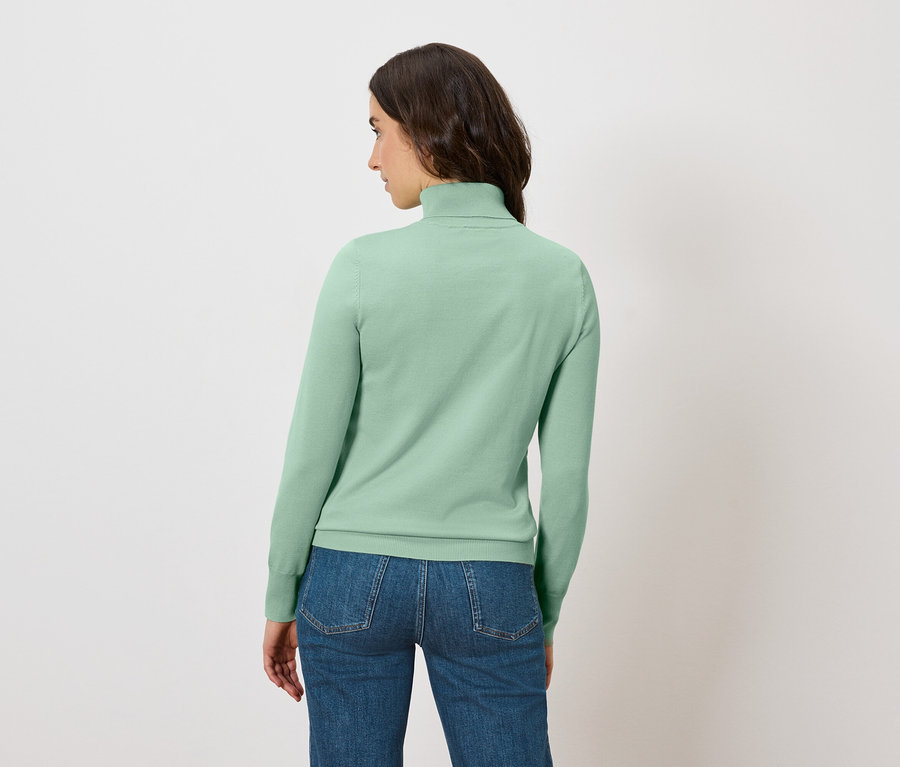 Žena z pohľadu zozadu má na sebe svetlozelený rolák a džínsy.