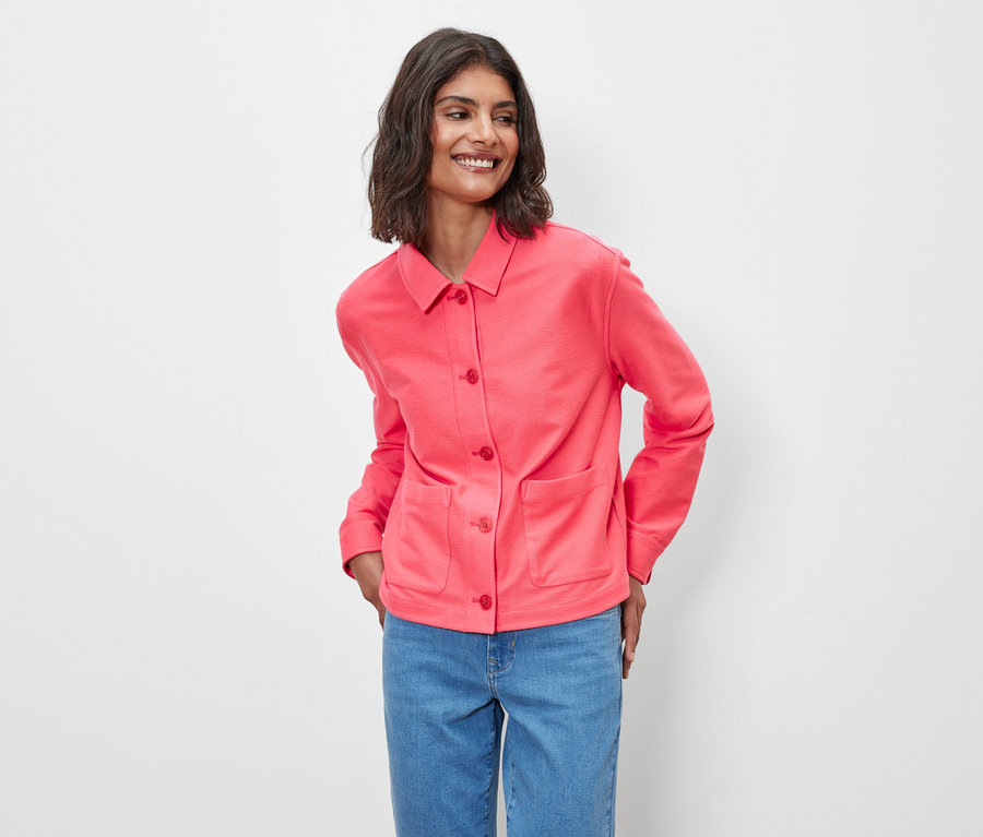 Žena pózuje v ružovej džersejovej bunde.