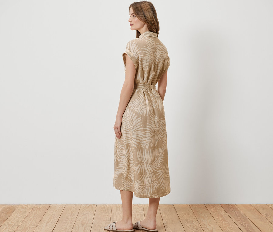 Žena stojí bokom a má na sebe ľanové šaty s potlačou.