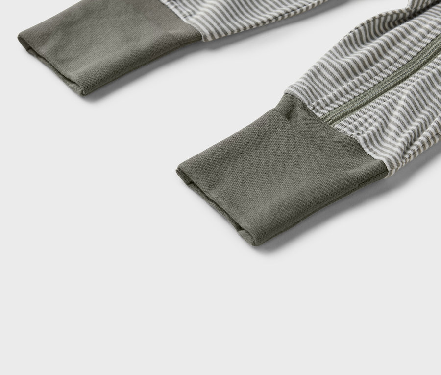 Rukávy sivo-bieleho pruhovaného pyžama s celoprepínacím zipsom a olivovozelenými manžetami.