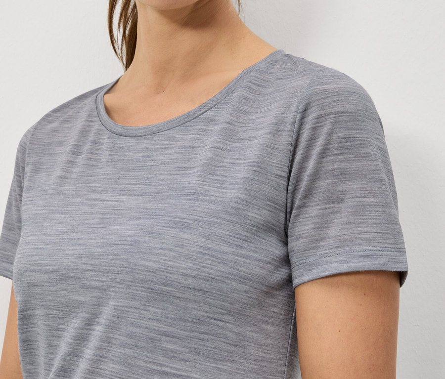 Detailný záber ženy v melírovanom, sivom tričku s krátkym rukávom.