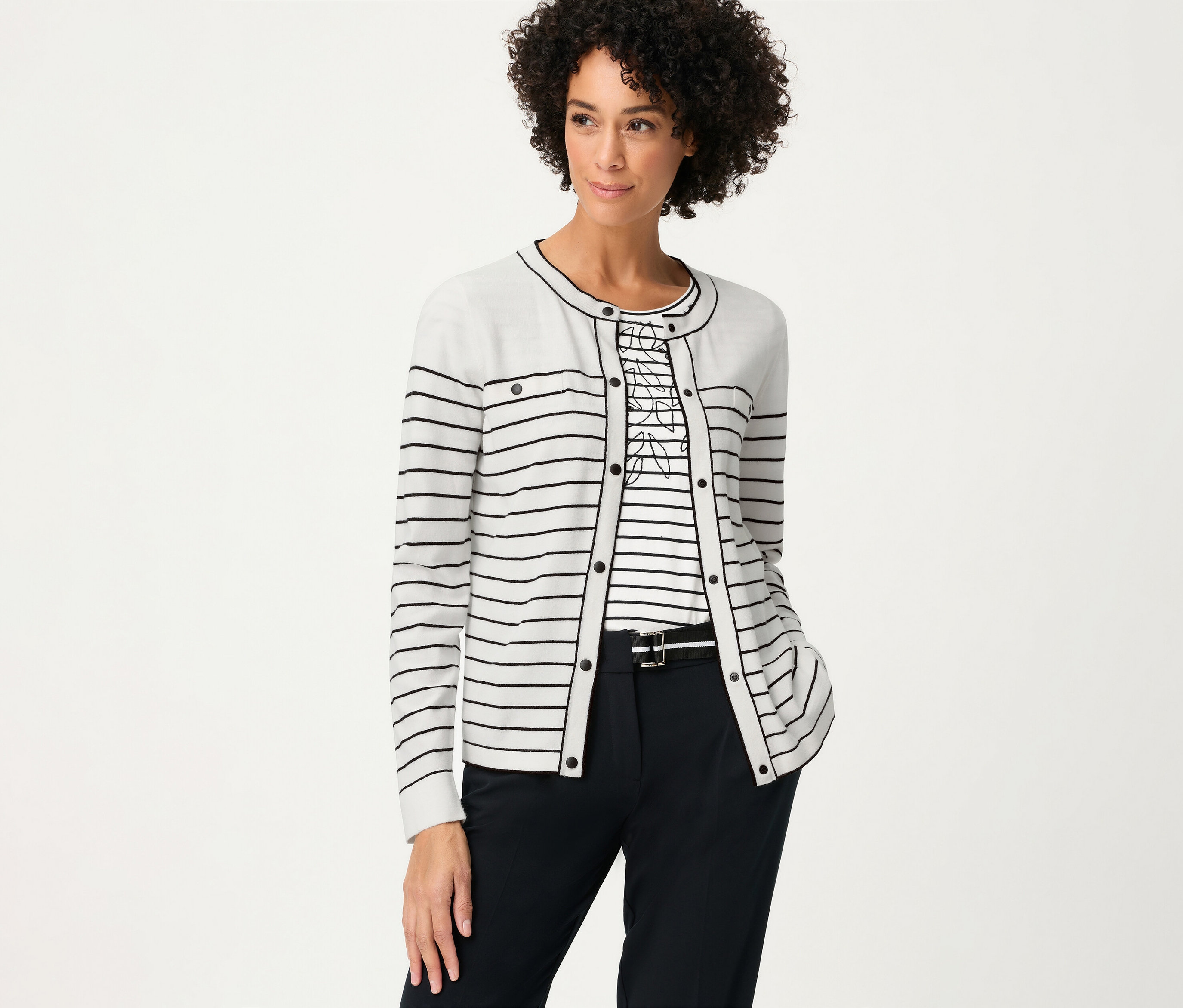 Žena v pruhovanom tope a kardigane Olsen »LA«. Má na sebe tmavé nohavice s opaskom.