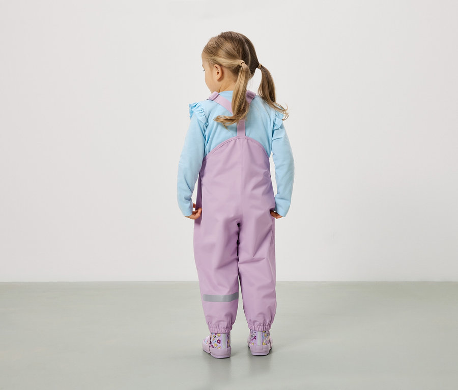 Dievča s vrkočmi stojí chrbtom k fotoaparátu a má na sebe fialové nohavice a topánky.