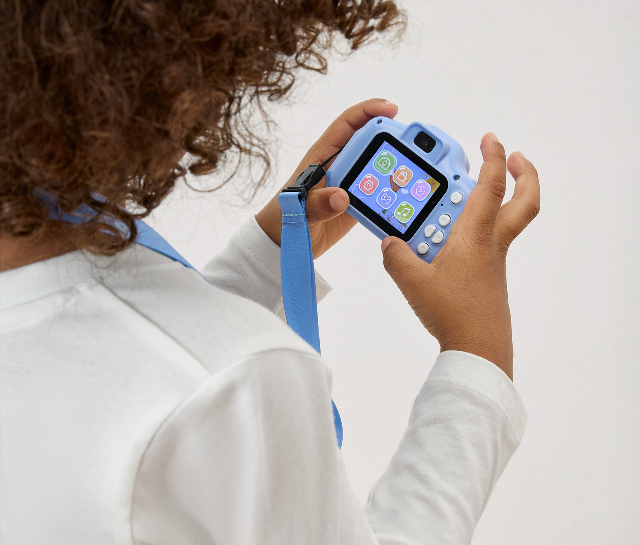 Dieťa drží pred sebou svetlomodrý hračkársky fotoaparát s modrým popruhom.