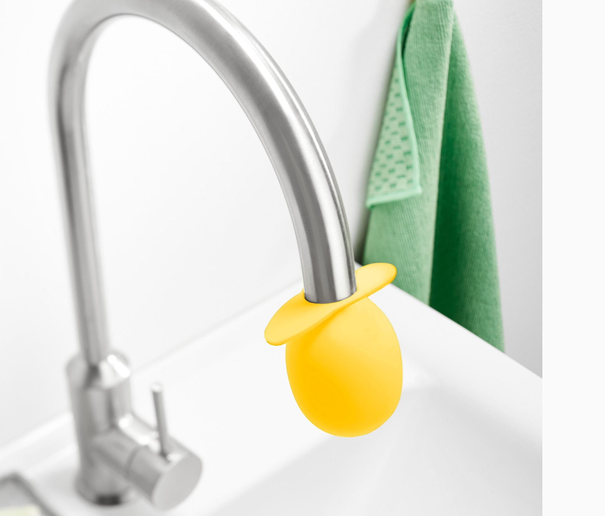 Žltý nadstavec na odvápnenie vodovodného kohútika na striebornom kohútiku v bielom umývadle.