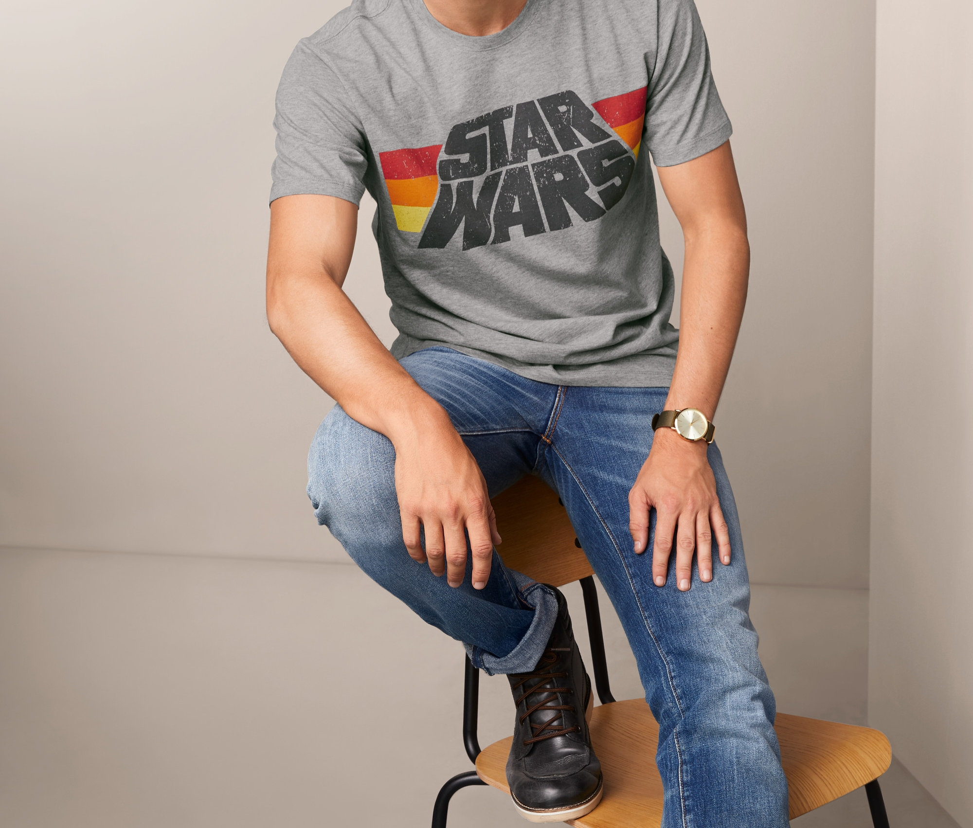 Muž sedí na stoličke a má na sebe sivé tričko s nápisom Star Wars.