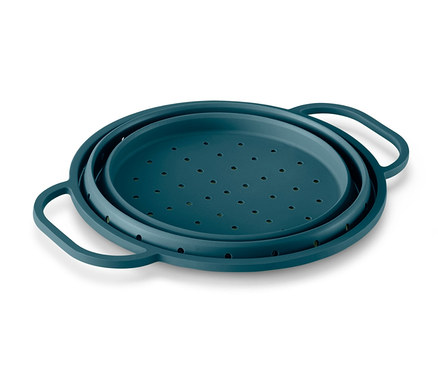 Tyrkysovo zelené priestorovo úsporné silikónové sitko leží na bielom povrchu.