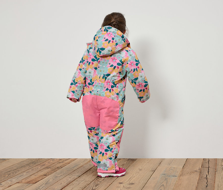 Pohľad zozadu na dieťa v kvetinovom overale s kapucňou a ružovými nohavicami.