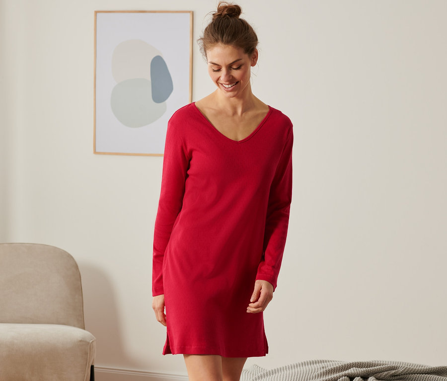 Usmievajúca sa žena má na sebe červenú ažúrovú nočnú košeľu.