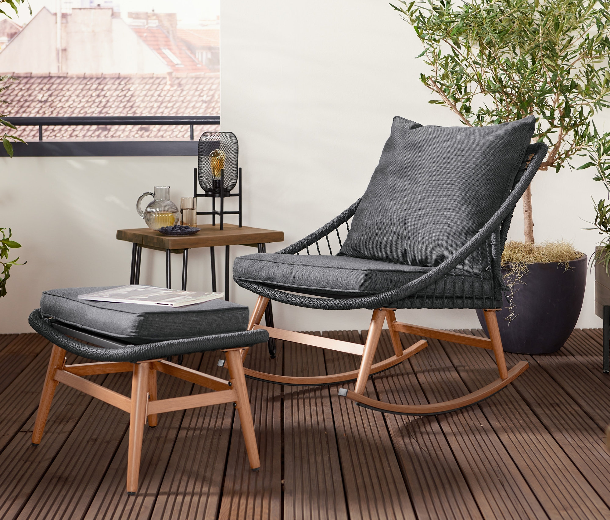 Hojdacie kreslo s podnožkou stojí na terase vedľa stolíka.