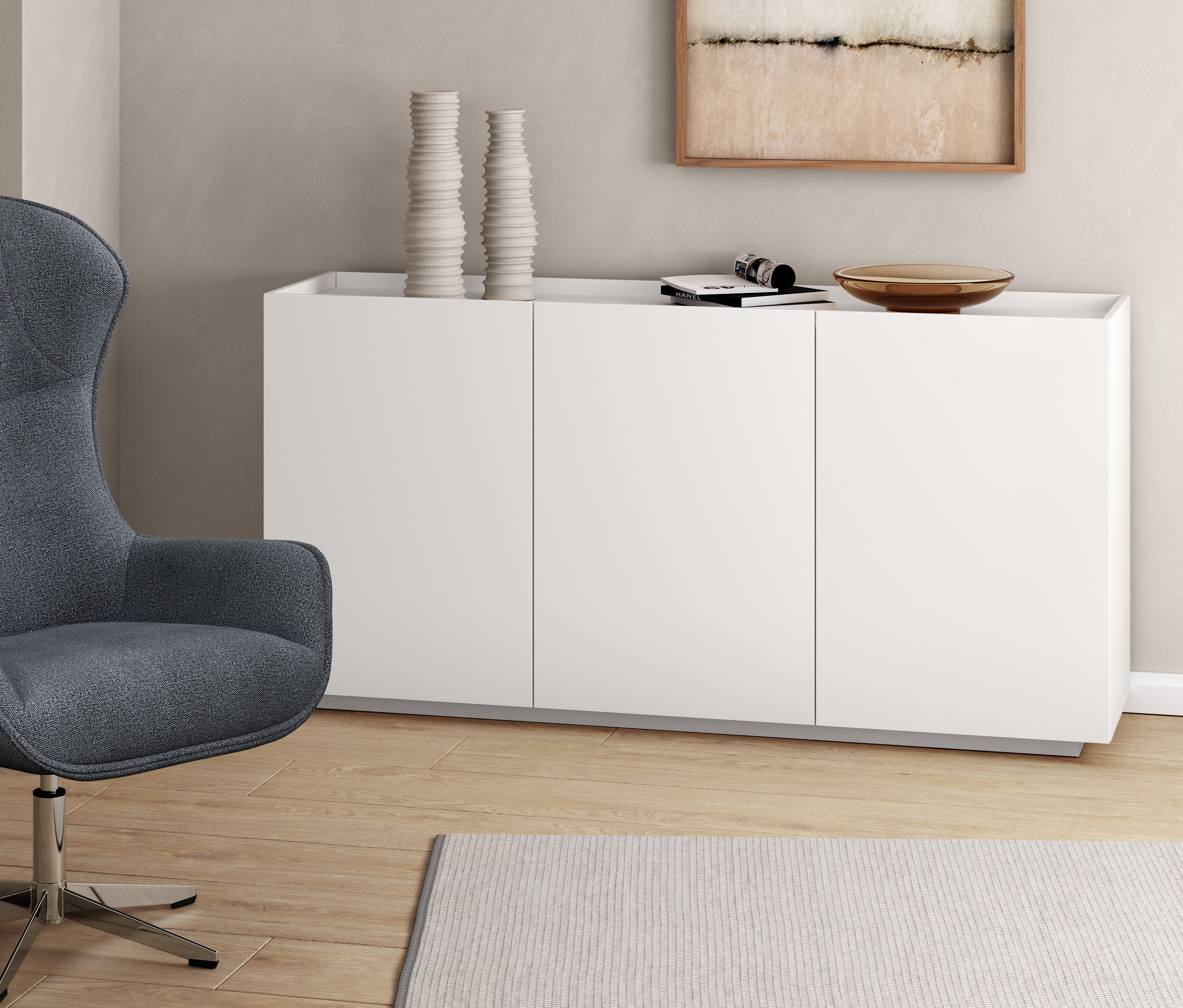 Sivé otočné kreslo vedľa bielej odkladacej skrinky.