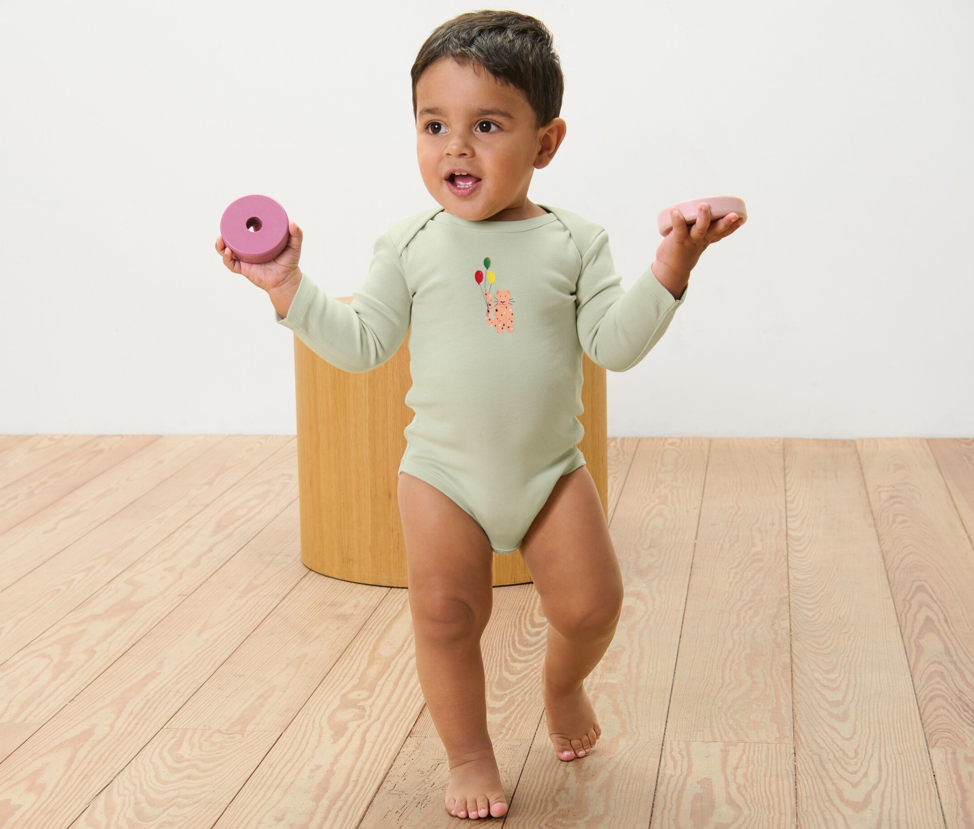 Batoľa v body s dlhým rukávom s potlačou drží v každej ruke hračku. Body pre bábätká s možnosťou prispôsobenia veľkosti, 5 ks