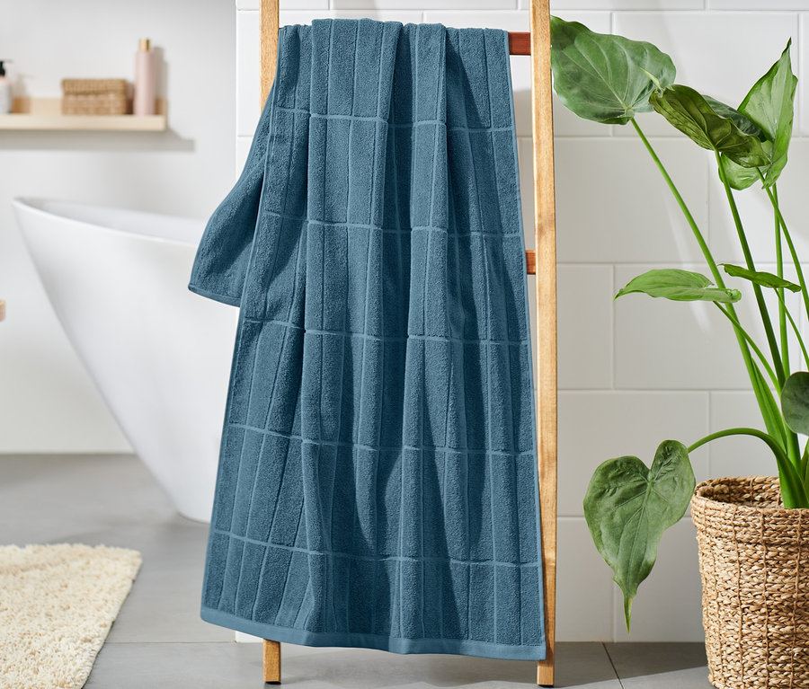 Modrá prémiová osuška visí na drevenom rebríku v kúpeľni.