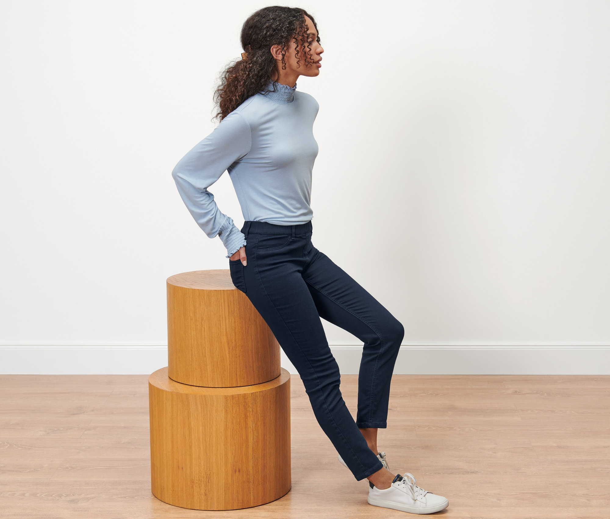 Žena sedí na drevenej stoličke a má na sebe tmavomodré tregínsy »Nelly«.