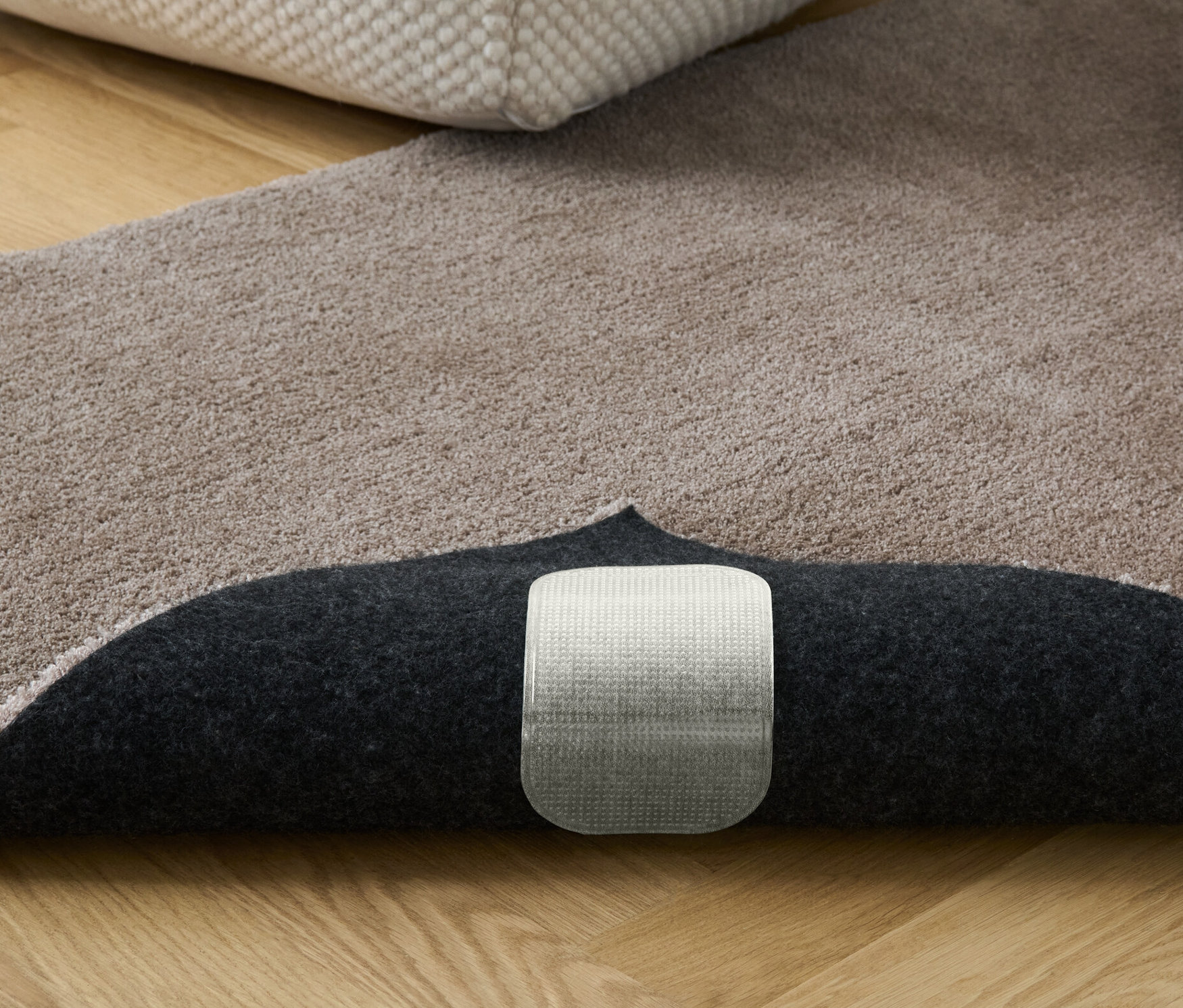 Béžový koberec s knihami a podnožkou. Viditeľné sú protišmykové podložky pod koberce, 4 ks.