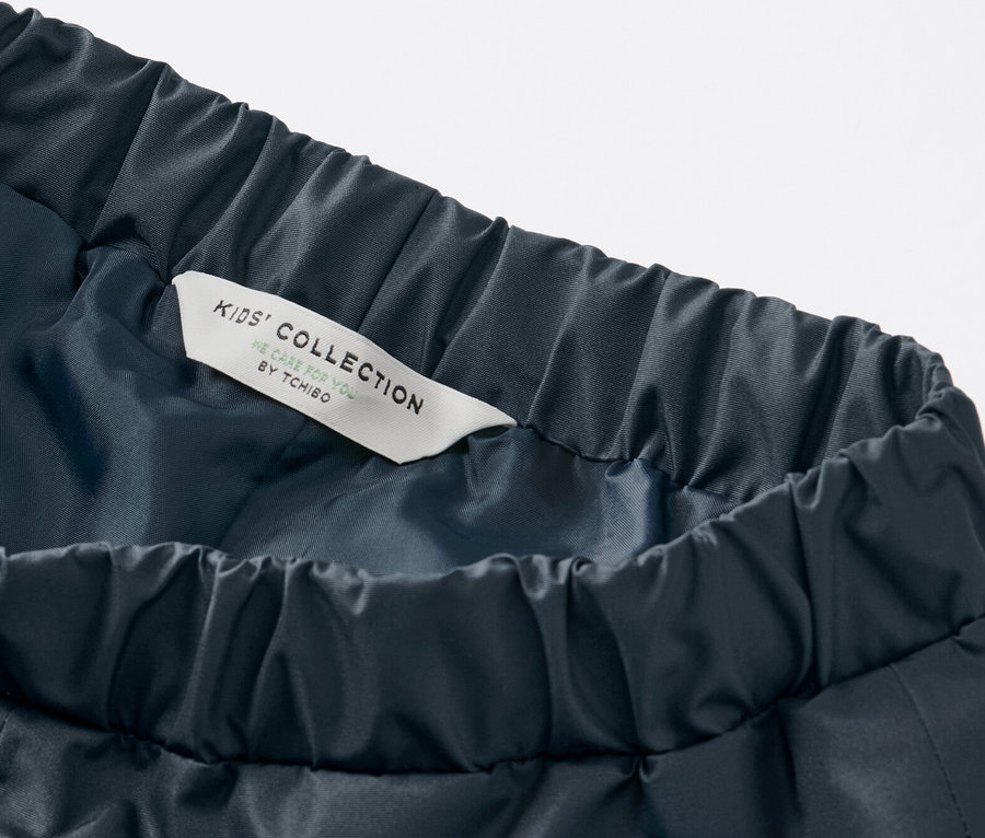 Detail detských nohavíc do dažďa tmavomodrej farby s elastickým pásom a štítkom Kids' Collection.