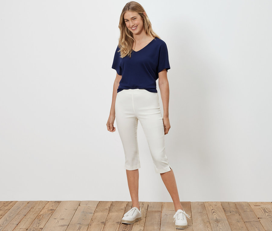 Žena pózuje v bielych trojštvrťových elastických nohaviciach.