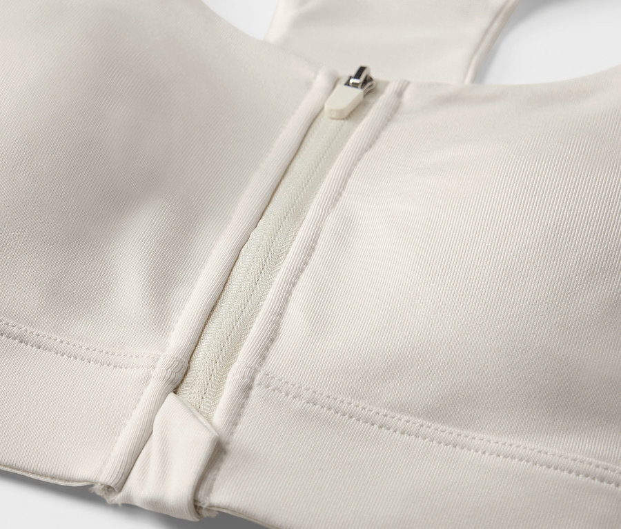 Detailný záber na športovú podprsenku s predným zipsom, farba offwhite.