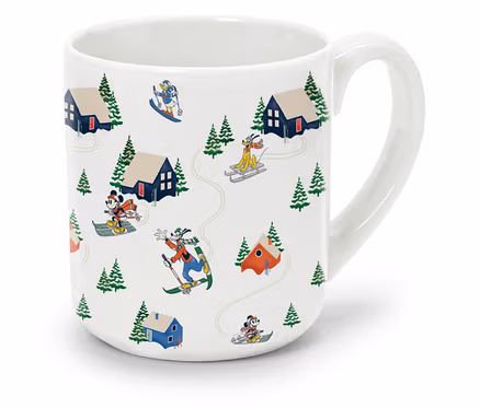 Biely hrnček s kreslenými obrázkami Mickey Mouse a Goofyho na lyžiach.