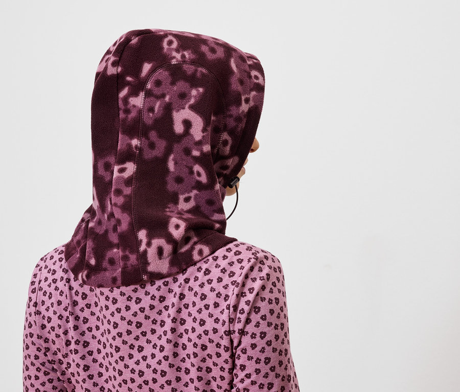 Pohľad zozadu na ženu s fialovým kvetinovým hidžábom a fialovou košeľou so vzorom srdca.