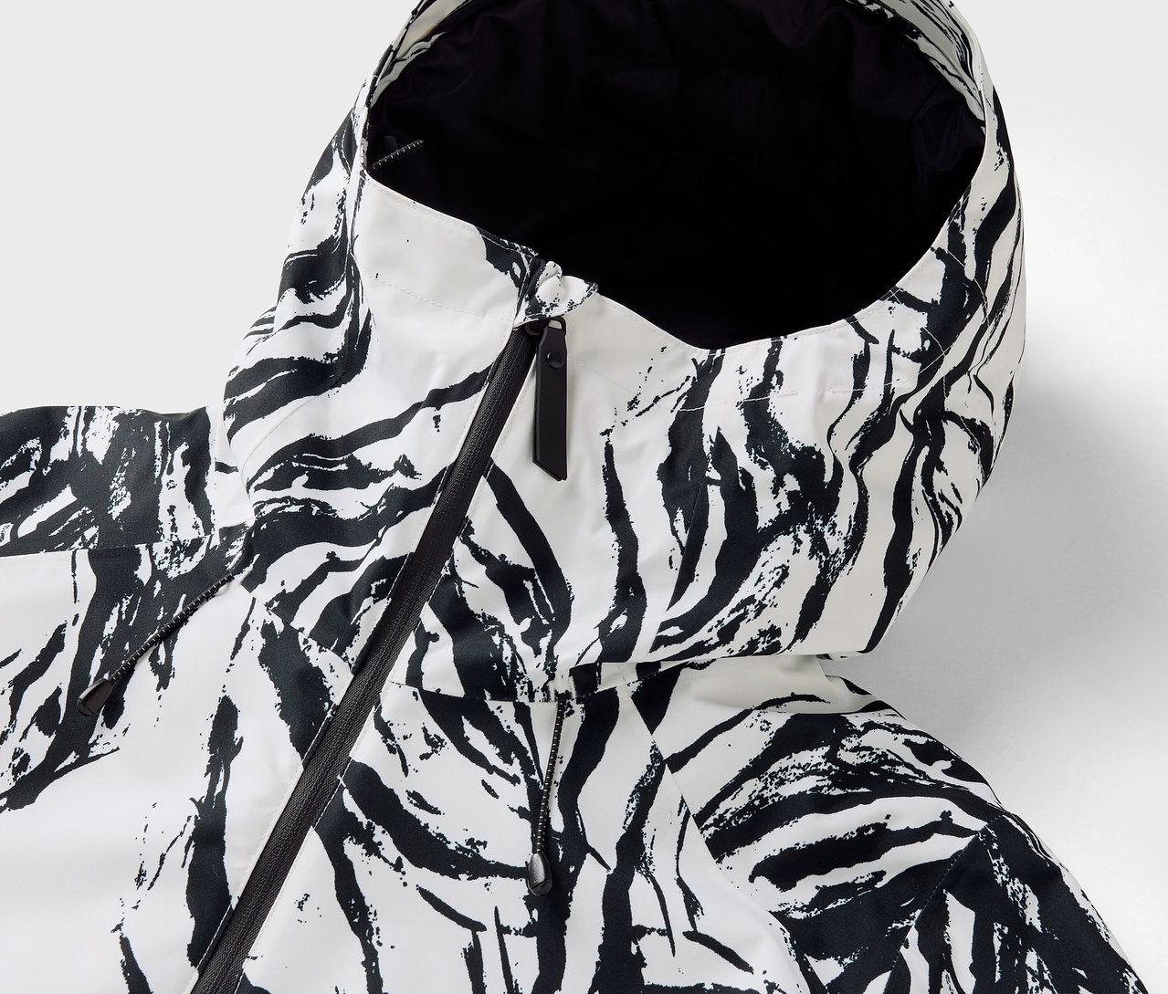 Detail kapucne bundy so vzorom zebry, čierny zips.