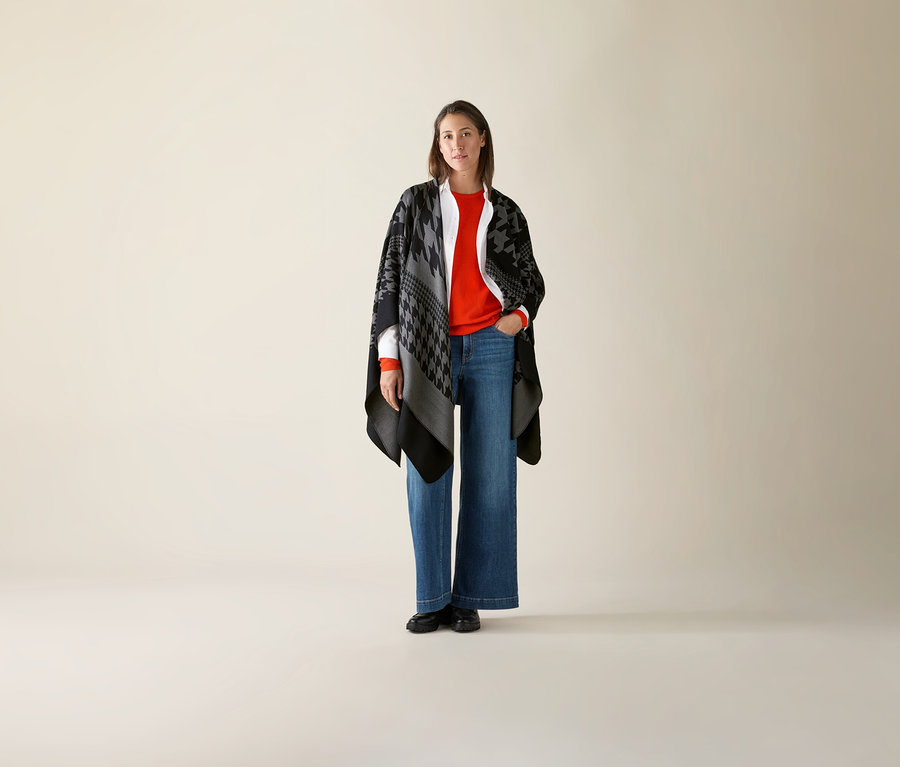 Žena stojí a má na sebe oranžový Mernio-Feinstrickpullover.